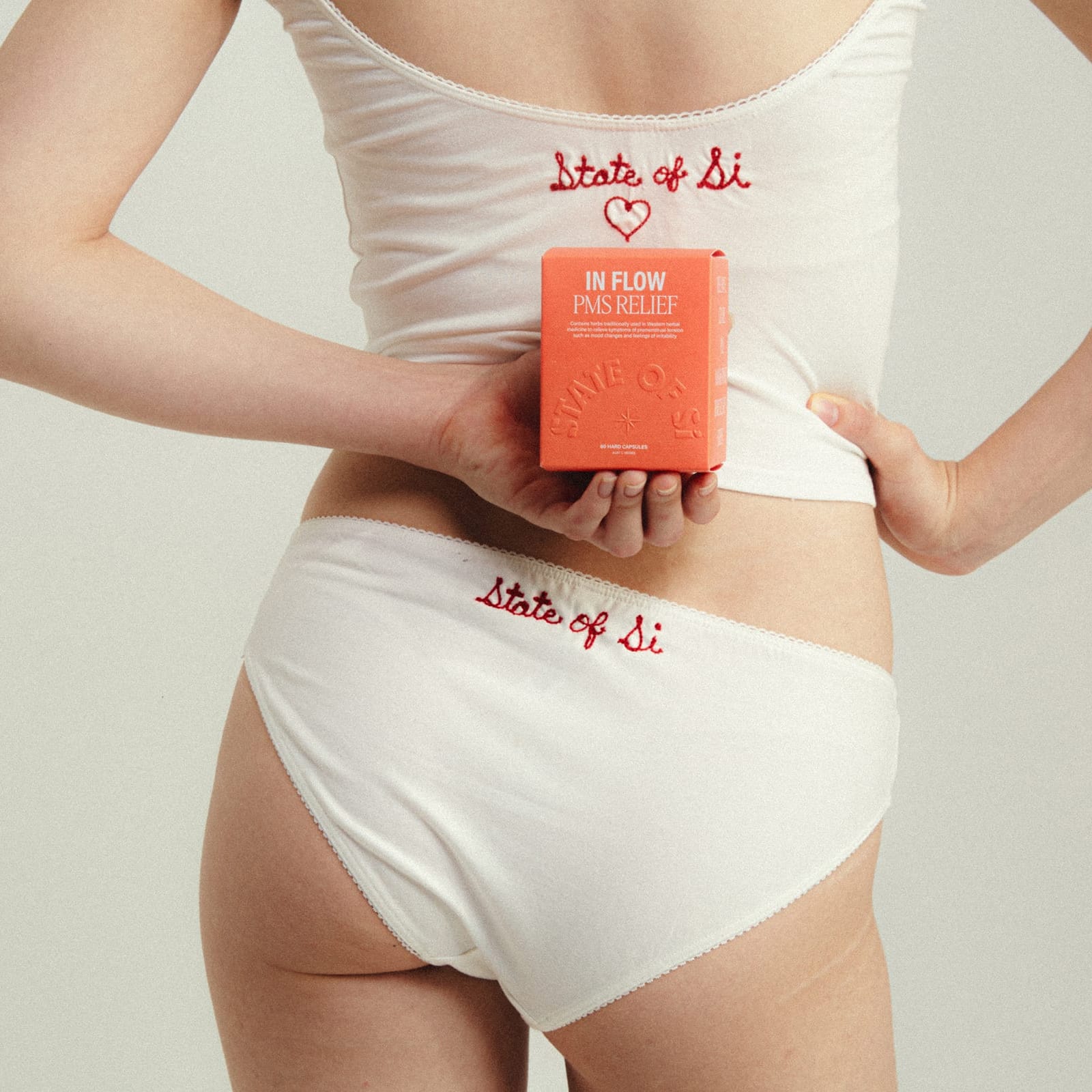 Model from behind holding In Flow PMS Relief clothing has State of Si and a heart stitched into it in red